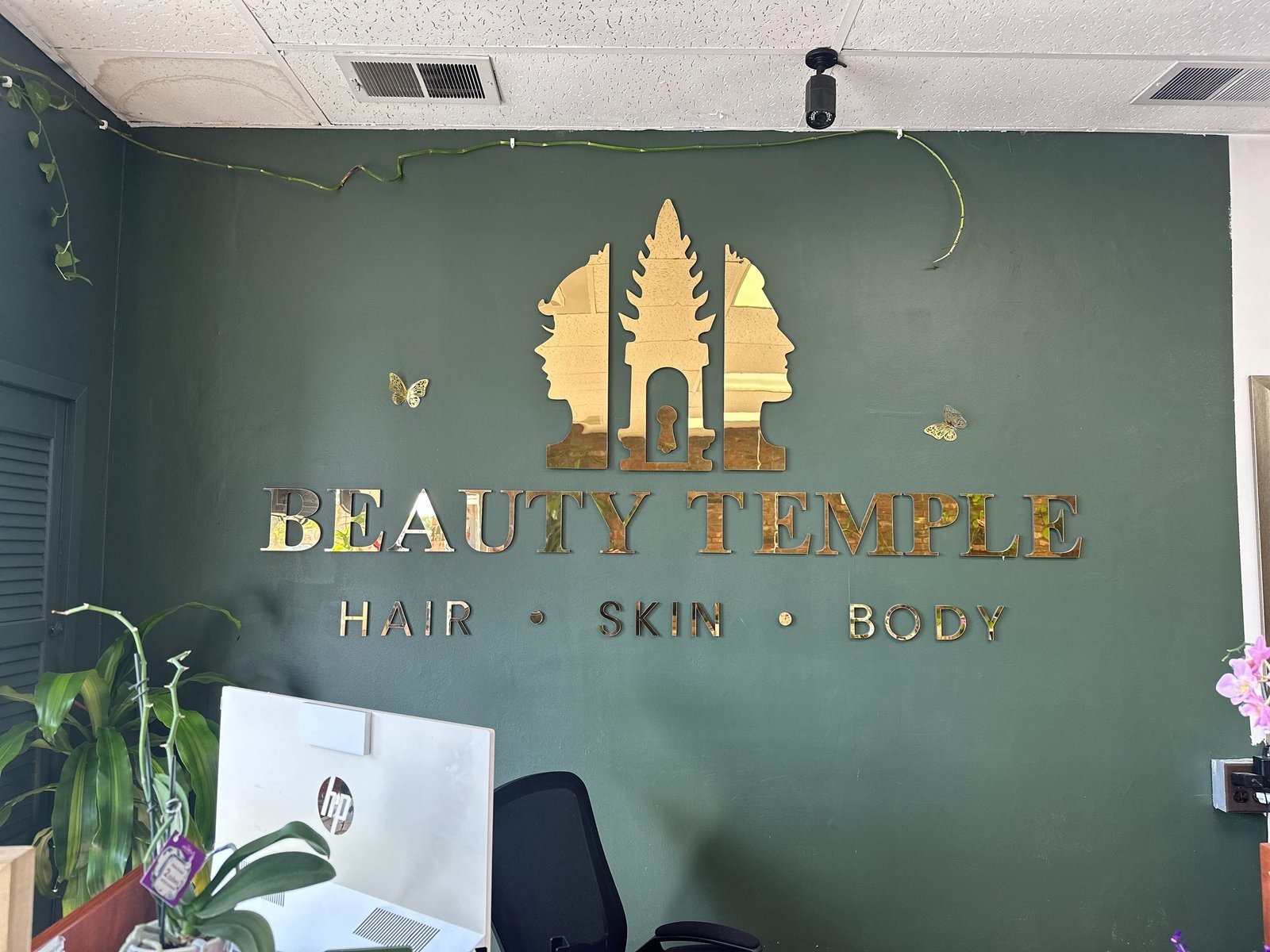 The gold Beauty Temple sign on the salon's emerald wall
